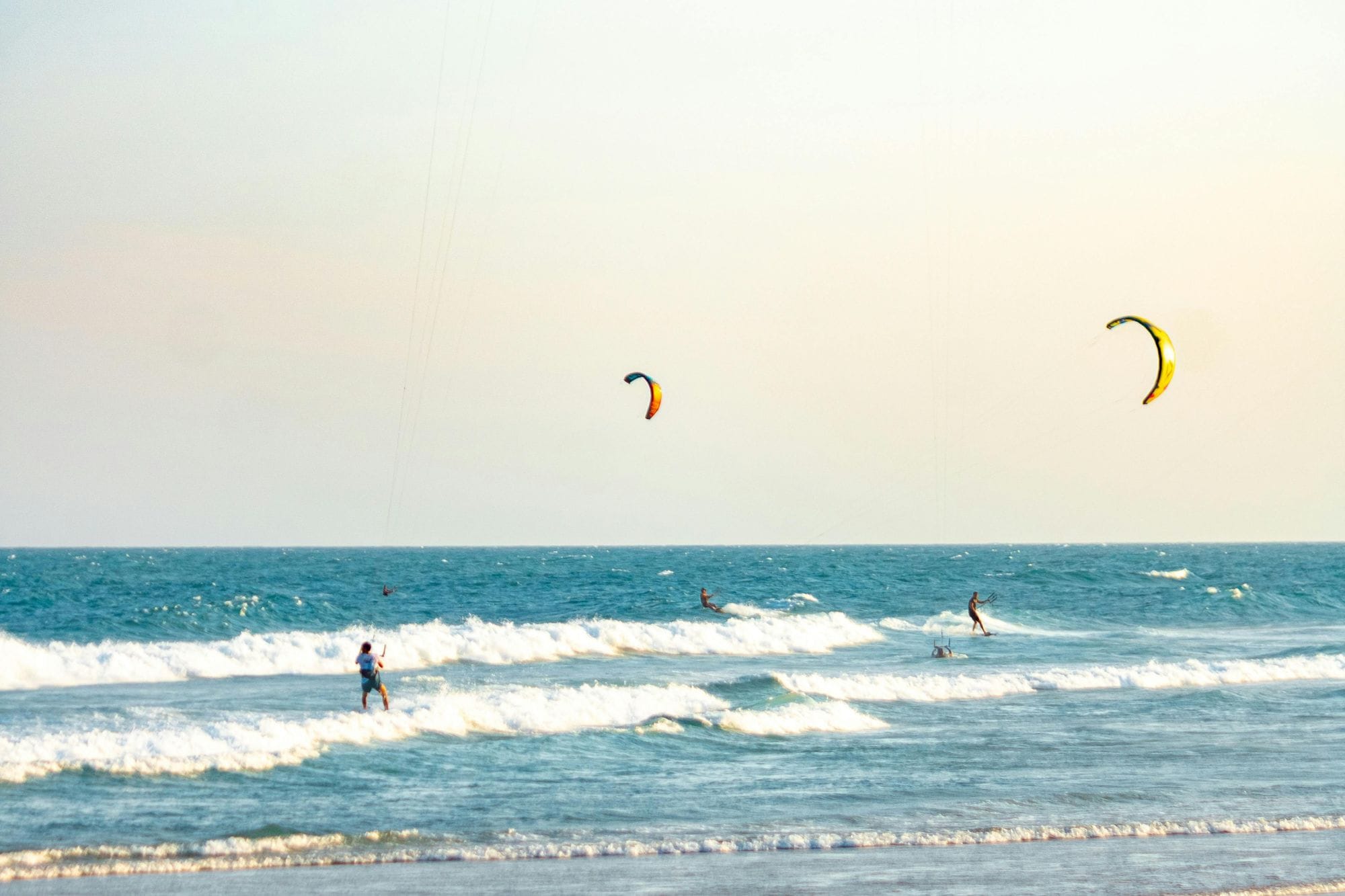 Kite surfers at the Baltic Sea during sundown.