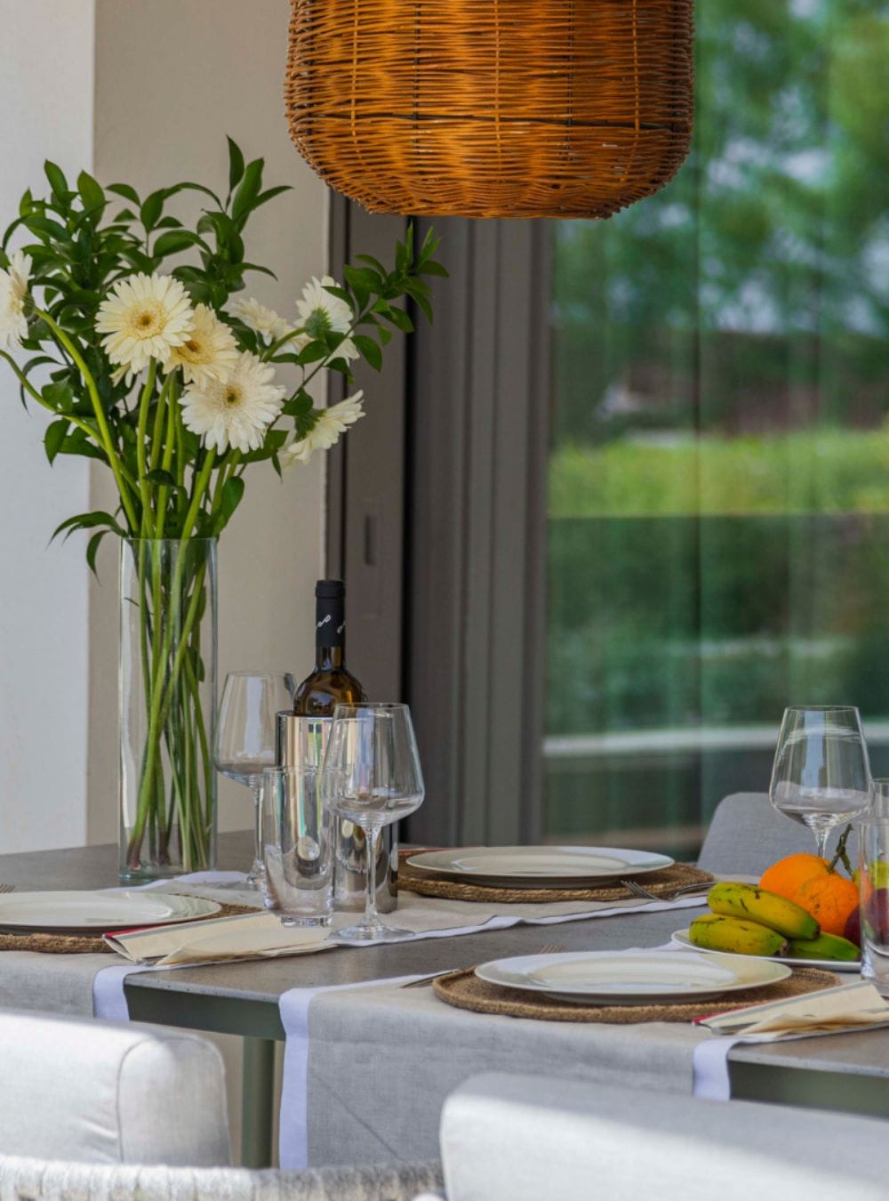 A set table with flowers and a bottle of wine.