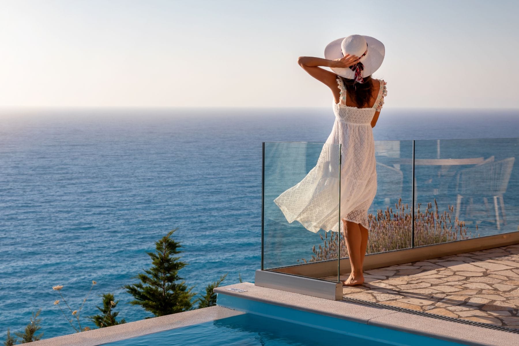 Woman on a terrace who is overlooking the ocean.