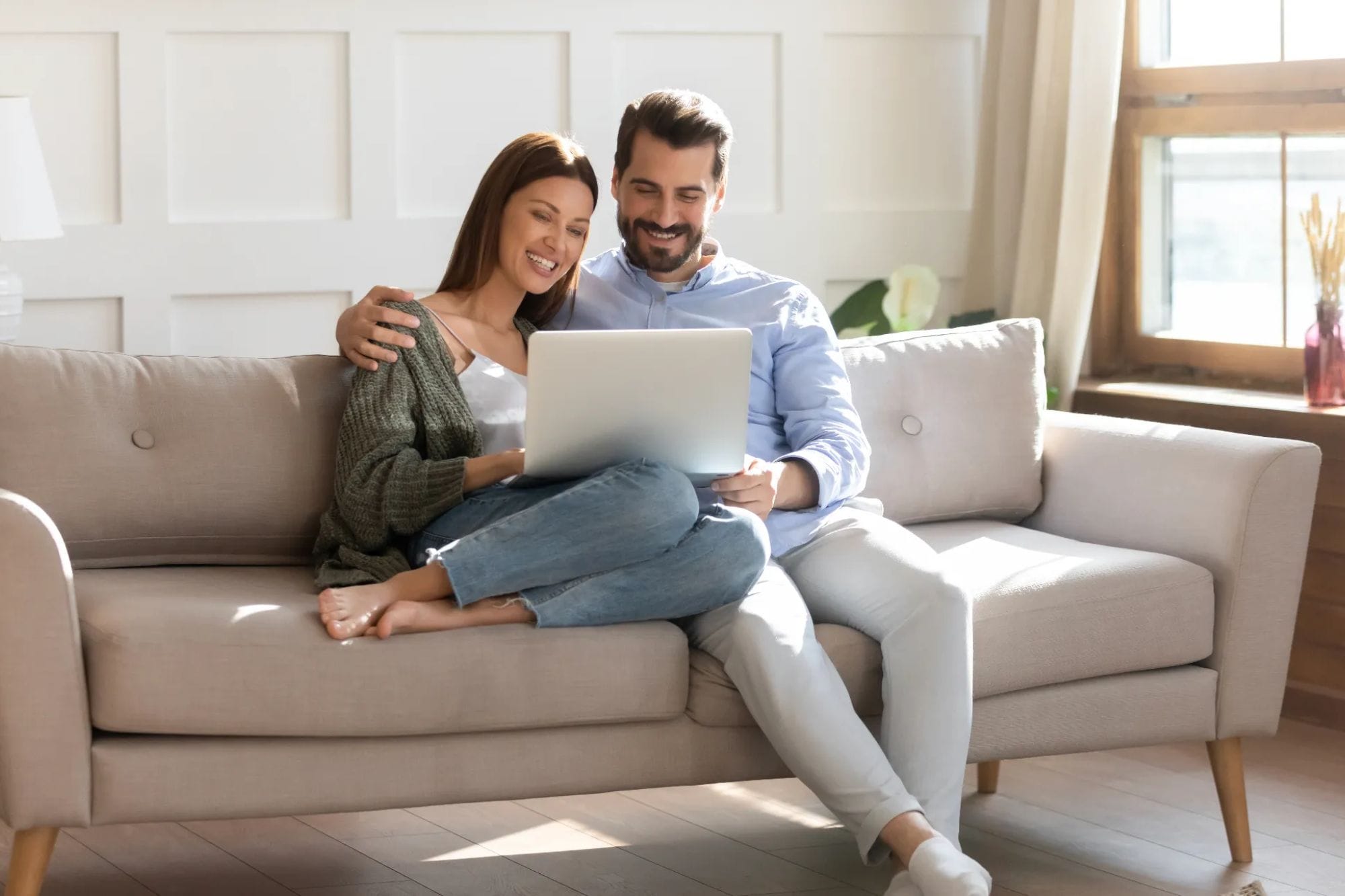 Couple sitting on the couch and using a laptop.